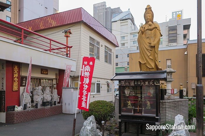 A statue of Kannon, the Buddhist goddess of mercy, and below her a small shrine to the lucky gods Ebisu and Daikokuten